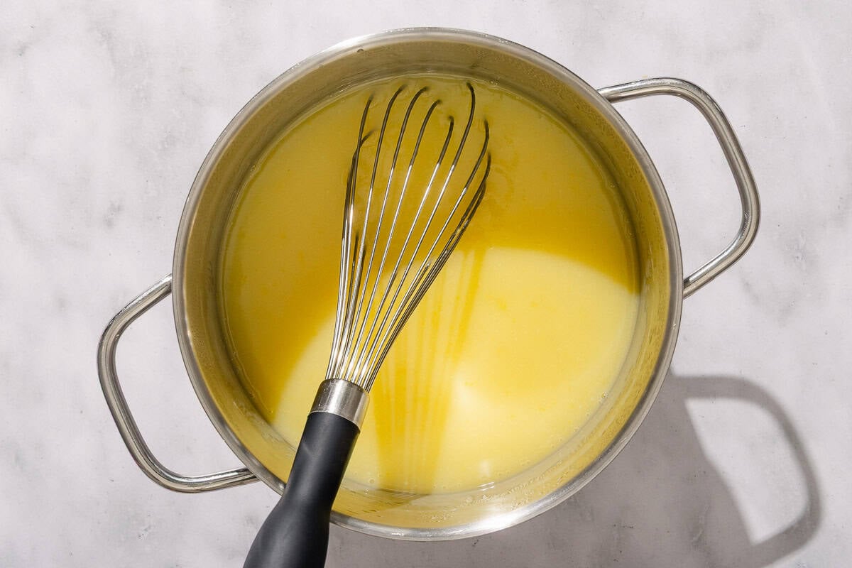 The lemon pudding is heated in a saucepan with a whisk.