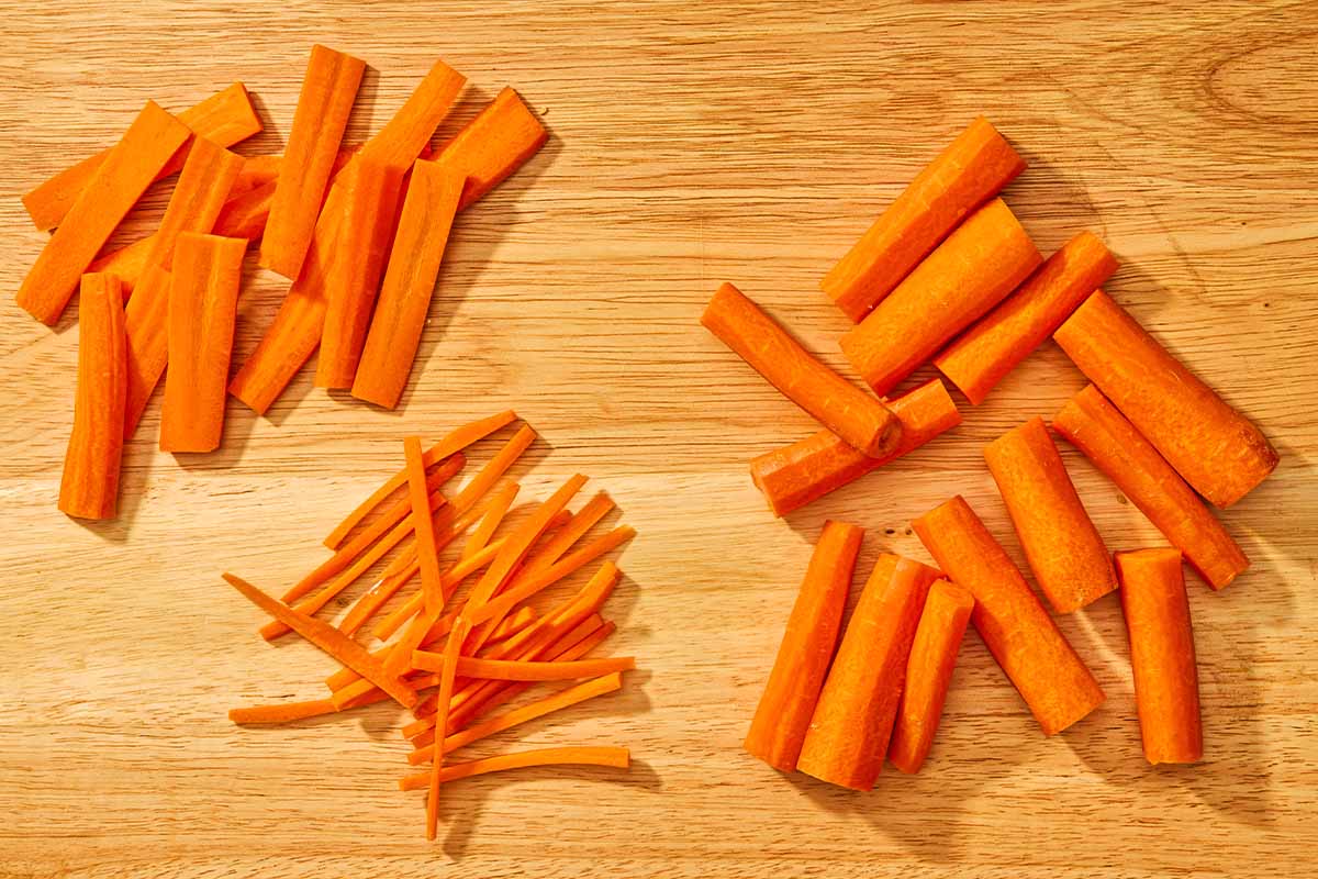 3 piles of sliced carrots on a cutting board.
