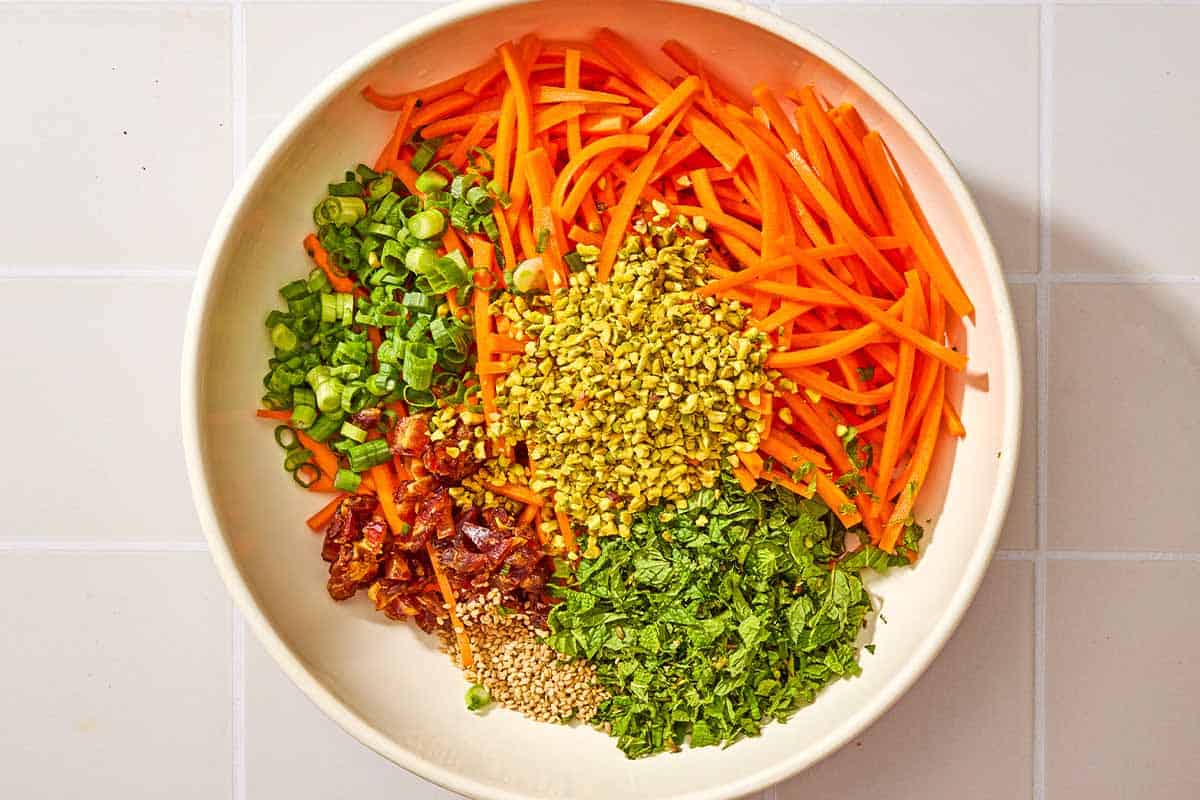 The ingredients for the carrot salad with herbs in a bowl just before being mixed together.