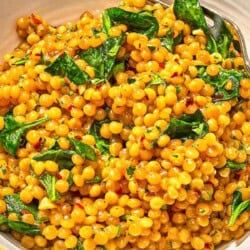 Spinach couscous in a bowl with a fork.