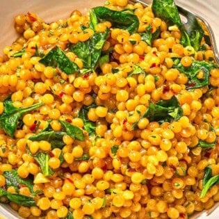 Spinach couscous in a bowl with a fork.