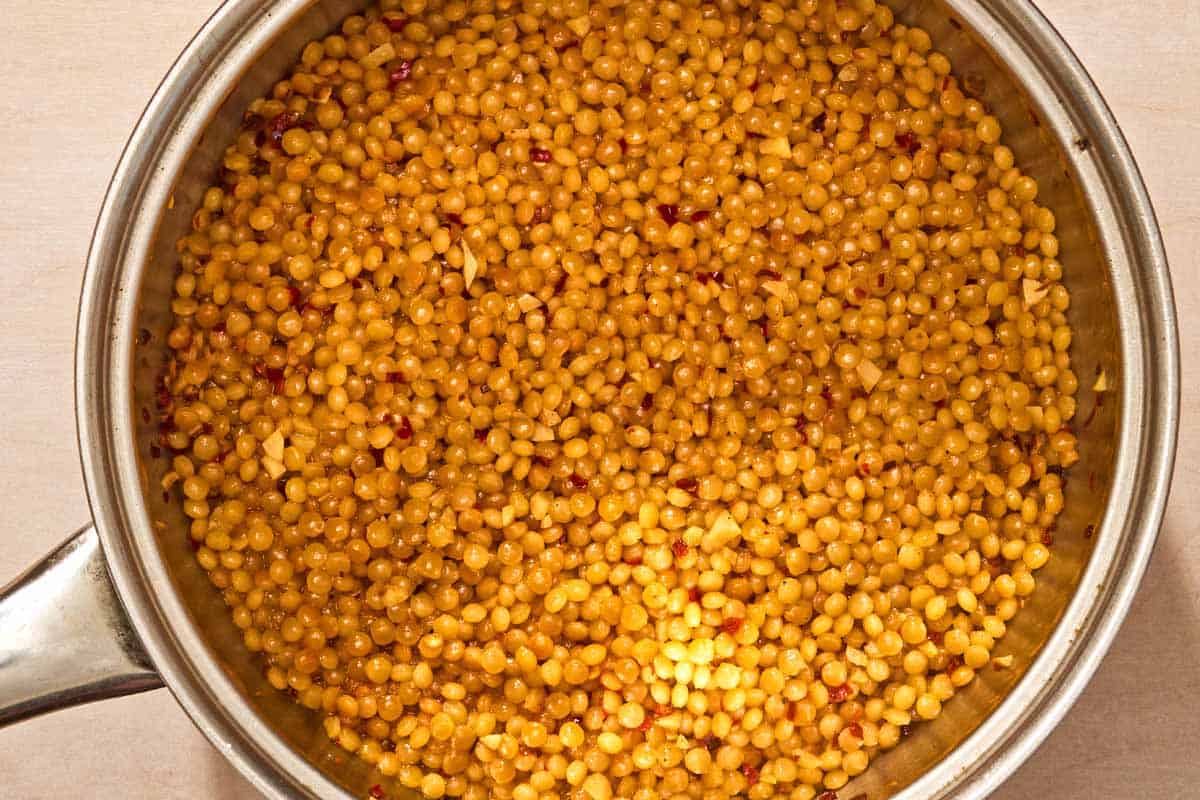 The seasoned cooked couscous for the spinach couscous in a saucepan.