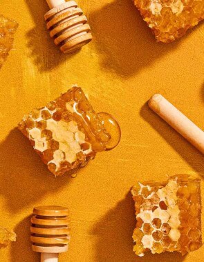 Five honey dippers with drizzles of honey and 5 honey combs.