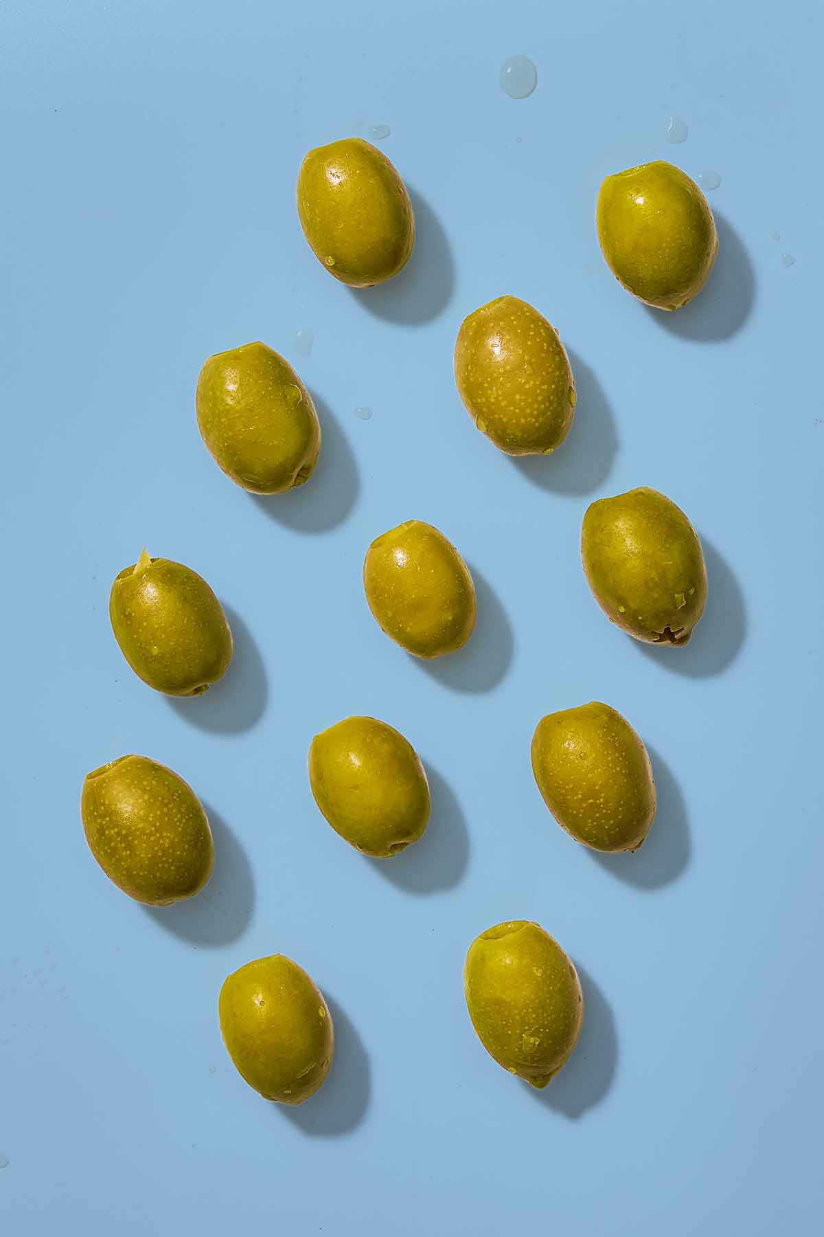 Several green olives placed evenly in rows.