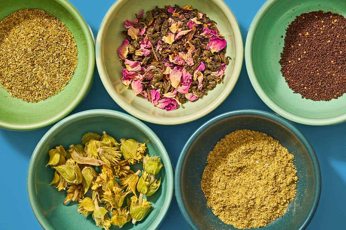 Five bowls, each containing different flavored tea leaves.