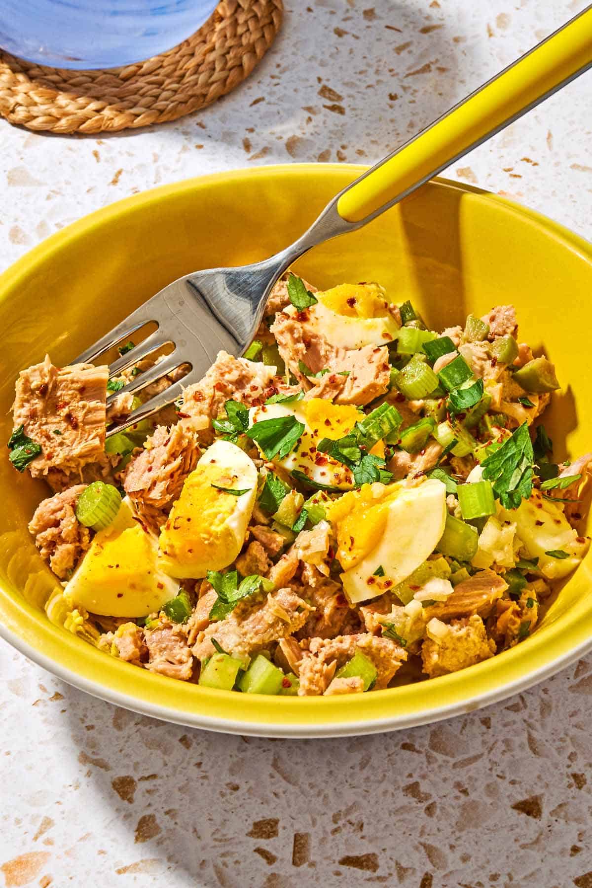A serving of the tuna salad with egg in a bowl with a fork.