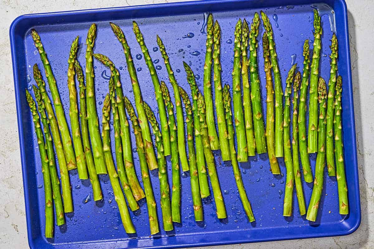 Roasted asparagus spread evenly on a baking sheet.