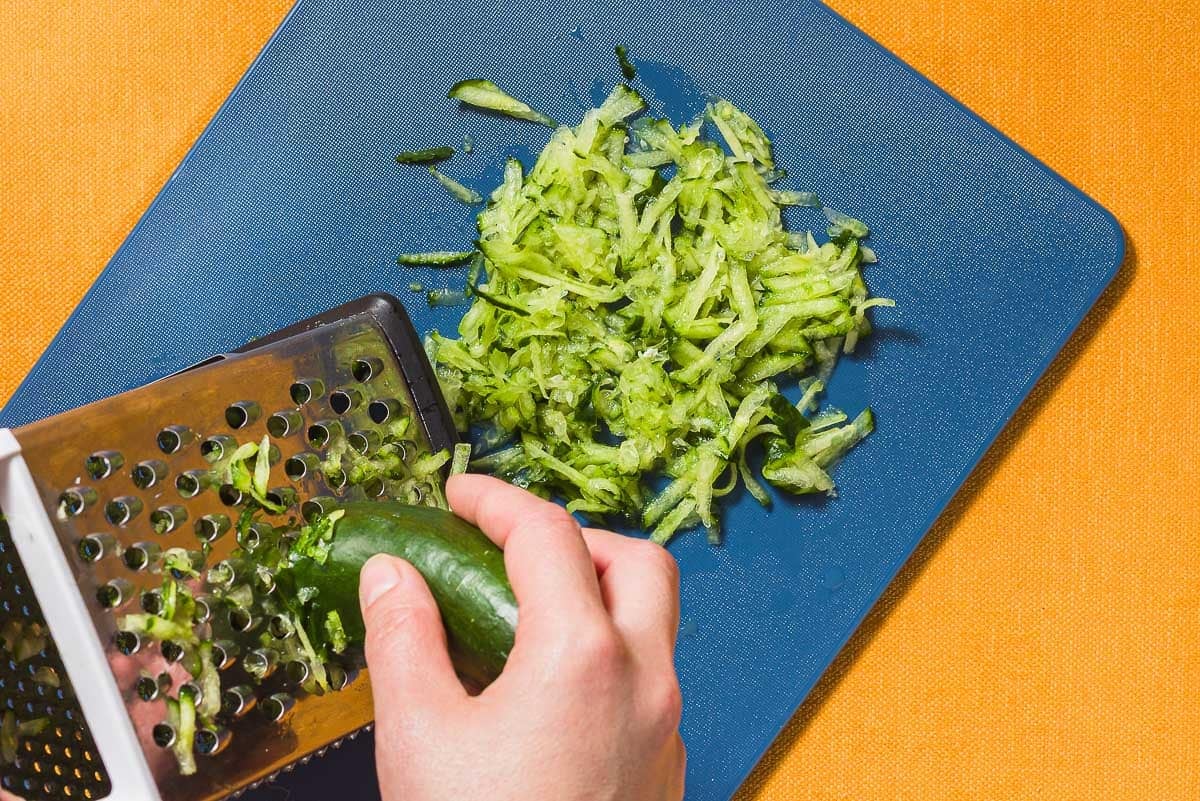 A cucumber for the Maast O'Khiar being grated onto a cutting board.