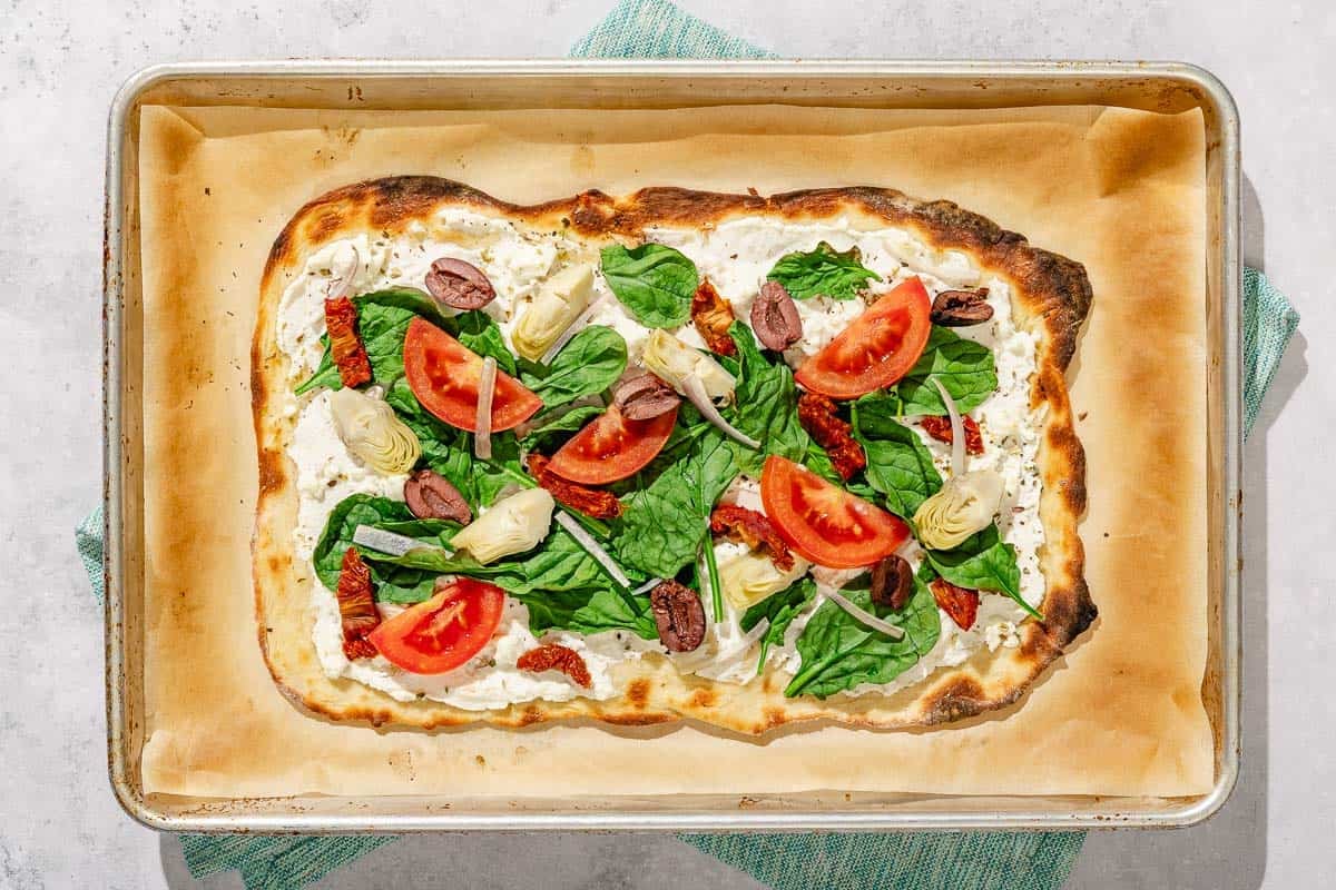 The baked flatbread pizza on a parchment lined sheet pan.