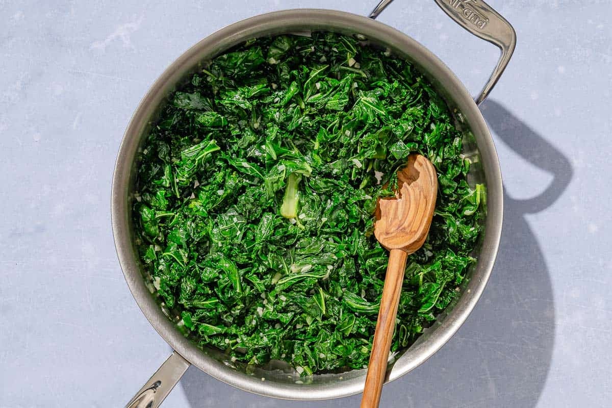Horta in a deep skillet with a wooden spoon.