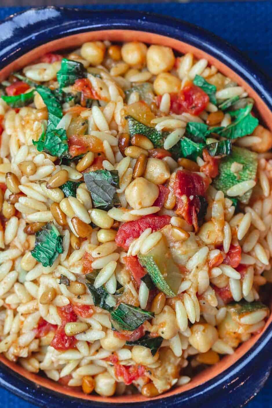Orzo with zucchini, chickpeas, and tomatoes. Garnished with fresh mint and toasted pine nuts