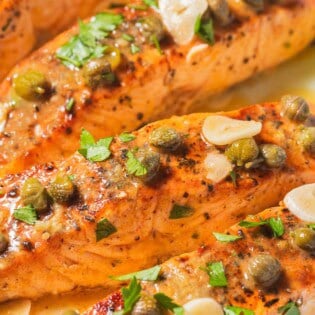 A close up of 4 salmon piccata fillets.