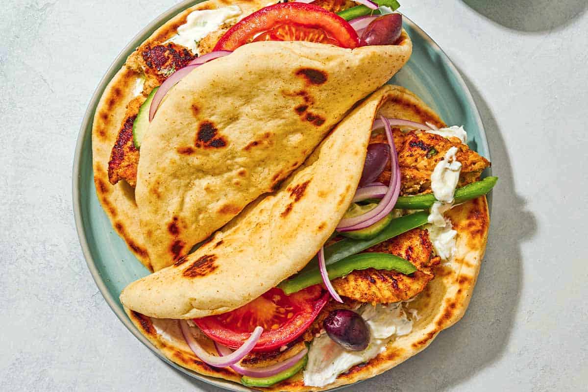 Two chicken gyros on a plate next.