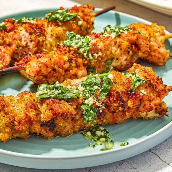 Three chicken spiedini skewers topped with the garlic parmesan herb sauce on a plate.