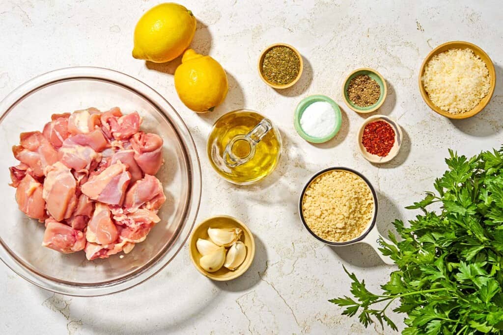 Ingredients for chicken spiedini including chicken thighs, olive oil, lemons, garlic, Italian seasoning, red pepper flakes, salt, black pepper, breadcrumbs, grated parmesan and parsley.