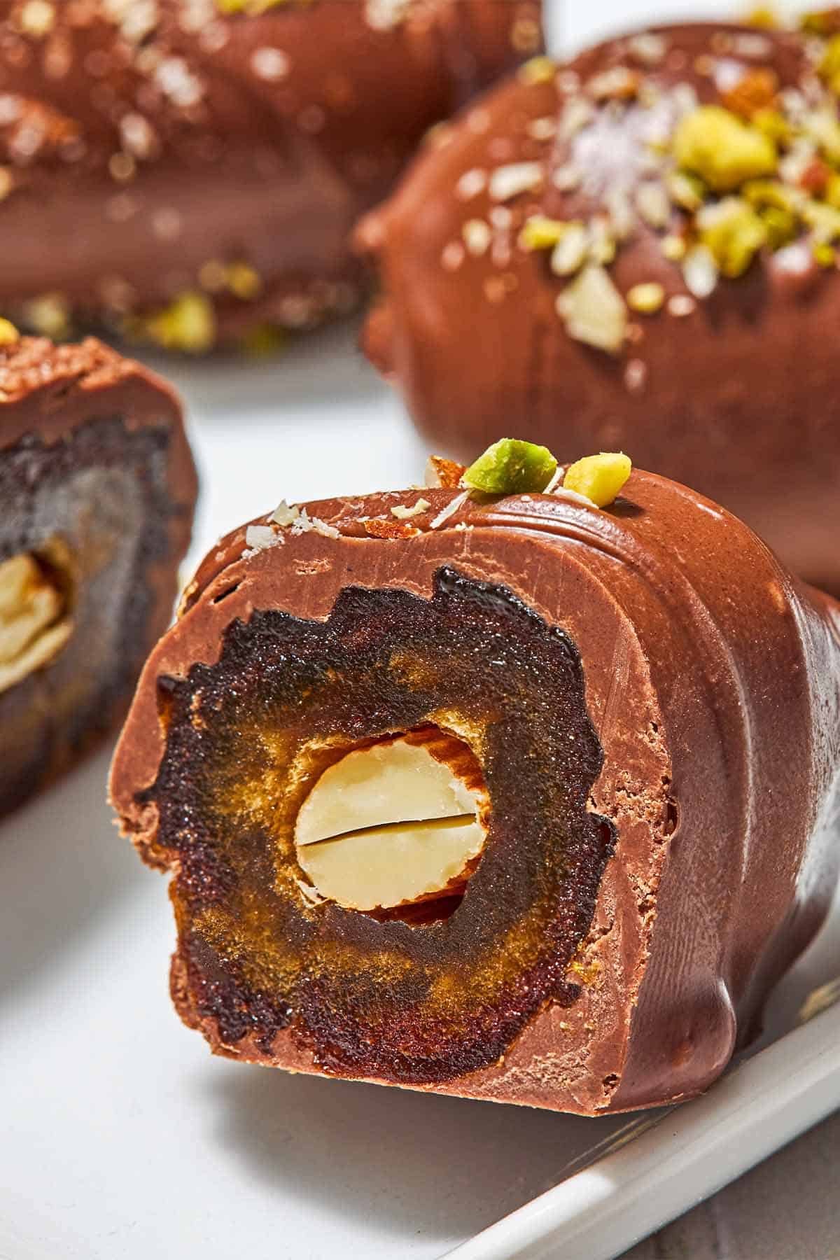 A close up of one half of a chocolate covered date showing an almond inside.