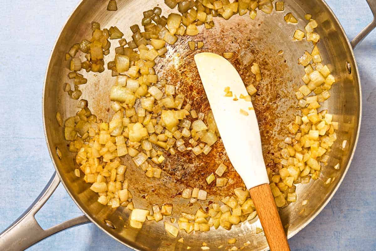The chopped onions for the risotto being sauteed in a deep skillet.