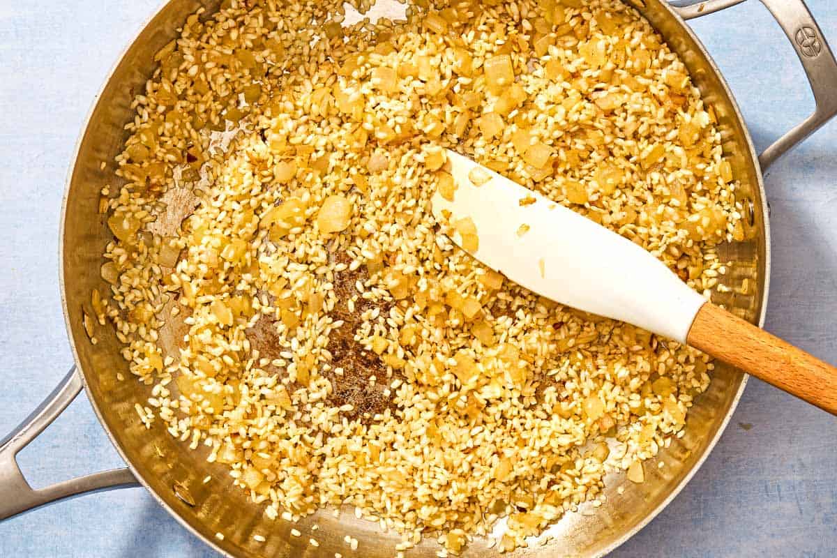 The rice for the risotto being toasted with the butter and chopped onion in a deep skillet.