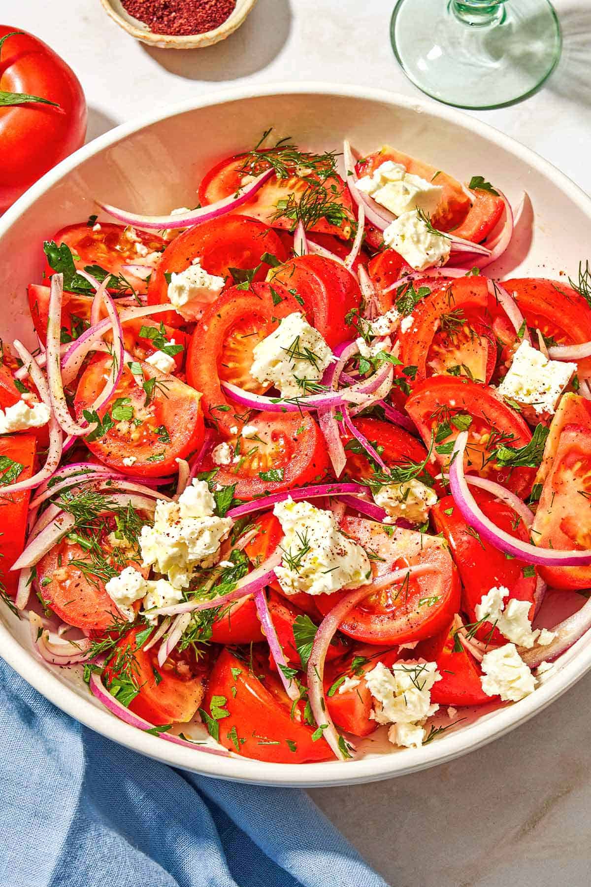 The tomato salad in a serving bowl. Tomato, feta, red onion and fresh herbs.