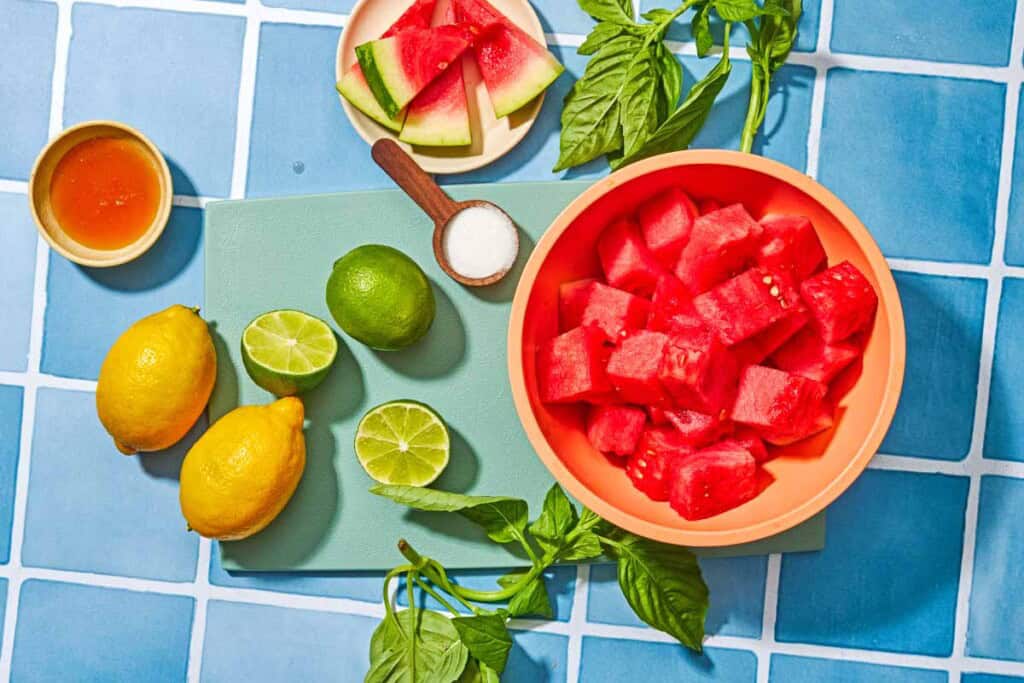 Ingredients for watermelon lemonade including watermelon, limes, lemons, sugar, honey and basil.