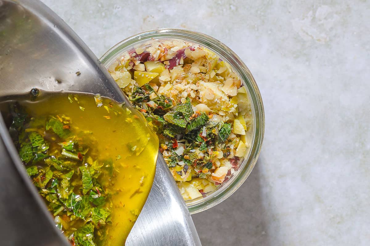 The warm marinade for being pourded over the olive-walnut mixture in a wide mouthed jar.