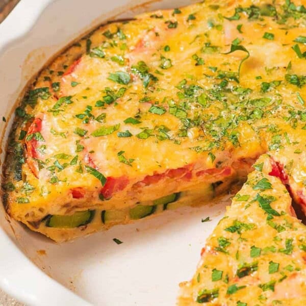 The crustless zucchini quiche in a baking dish with one slice removed.