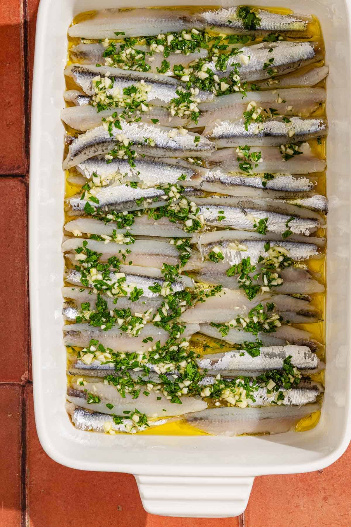 Boquerones marinating in a baking dish.