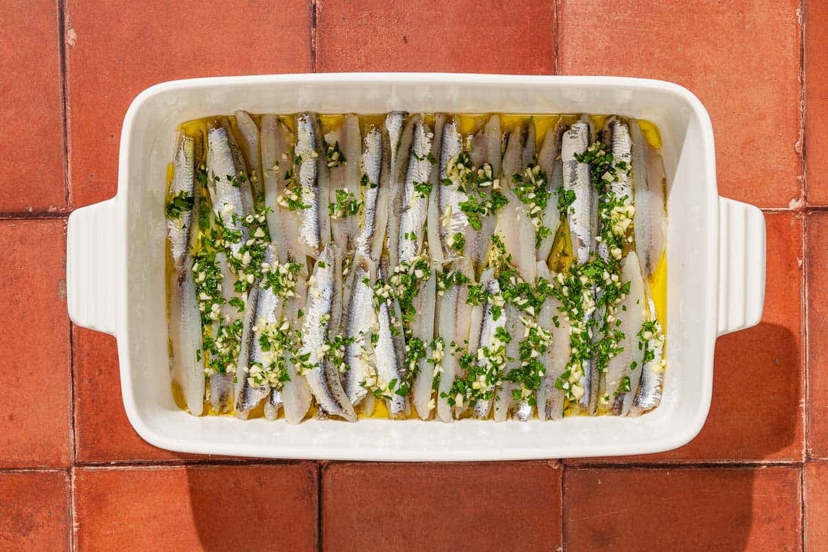 Boquerones marinating in a baking dish.