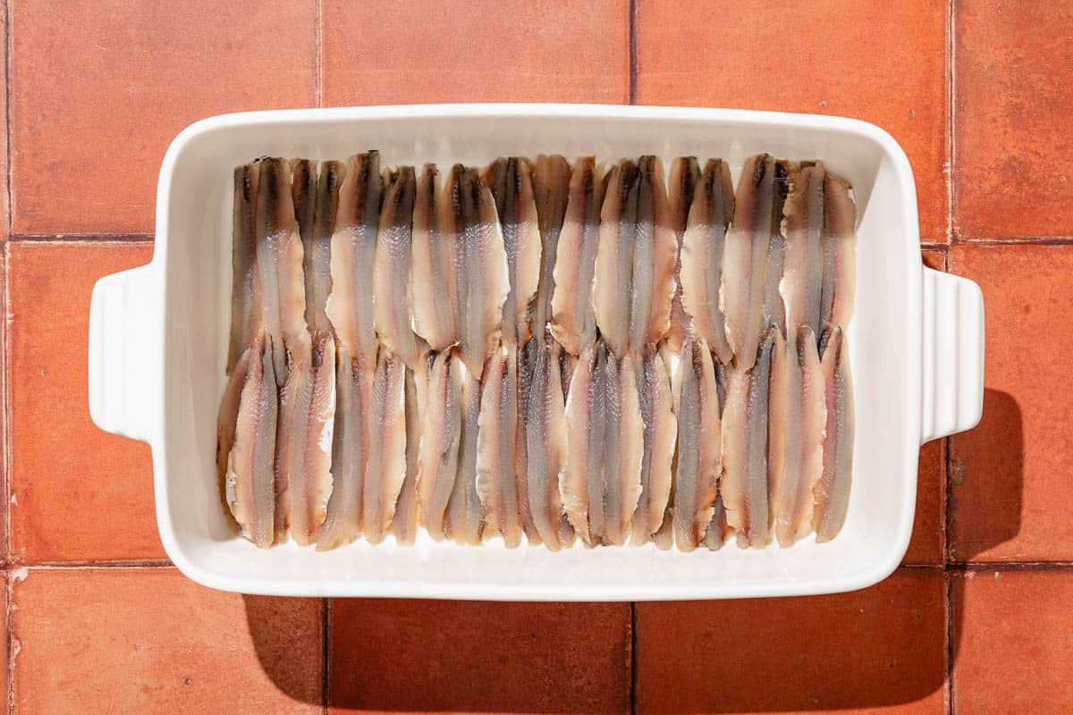Anchovy fillets spread evening in a baking dish.