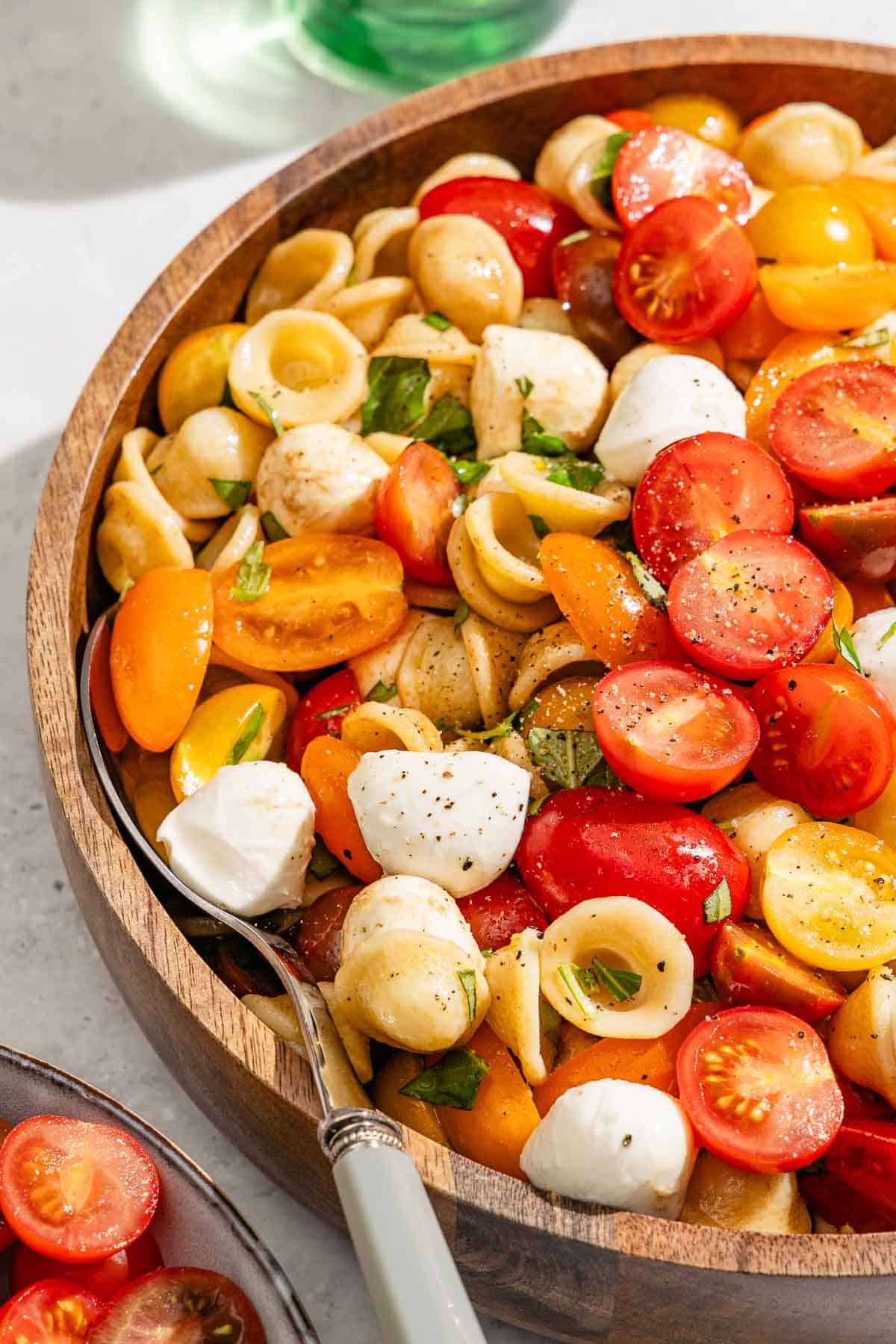 Caprese pasta salad in a serving bowl with a spoon.