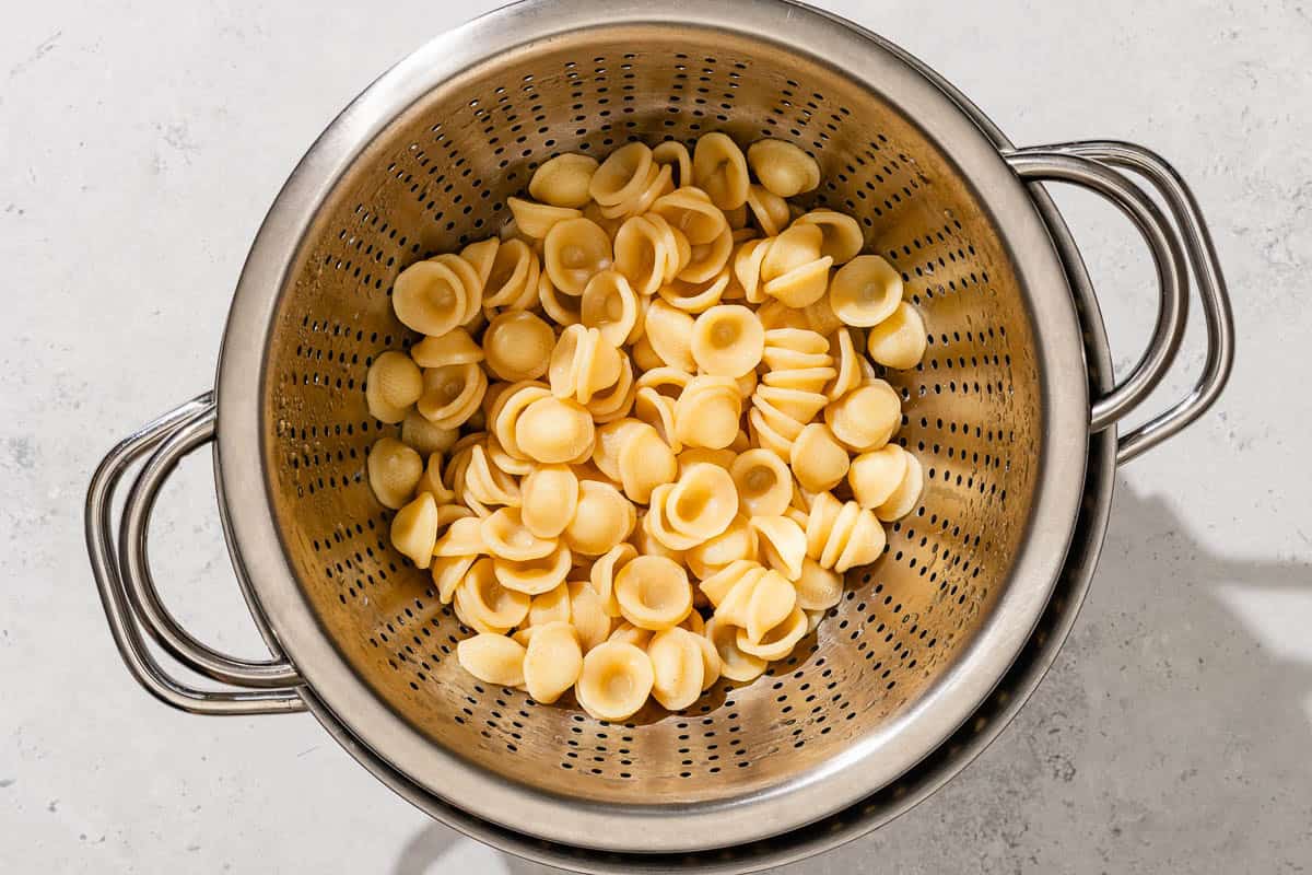 Orecchiette pasta in a strainer resting on a pot.