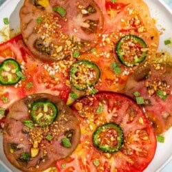 Heirloom tomato salad topped with dukkah and mint on a platter.