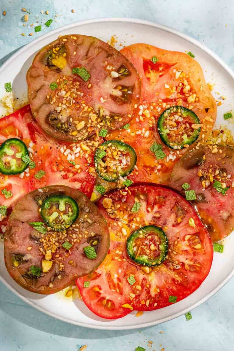 Heirloom tomato salad topped with dukkah and mint on a platter.