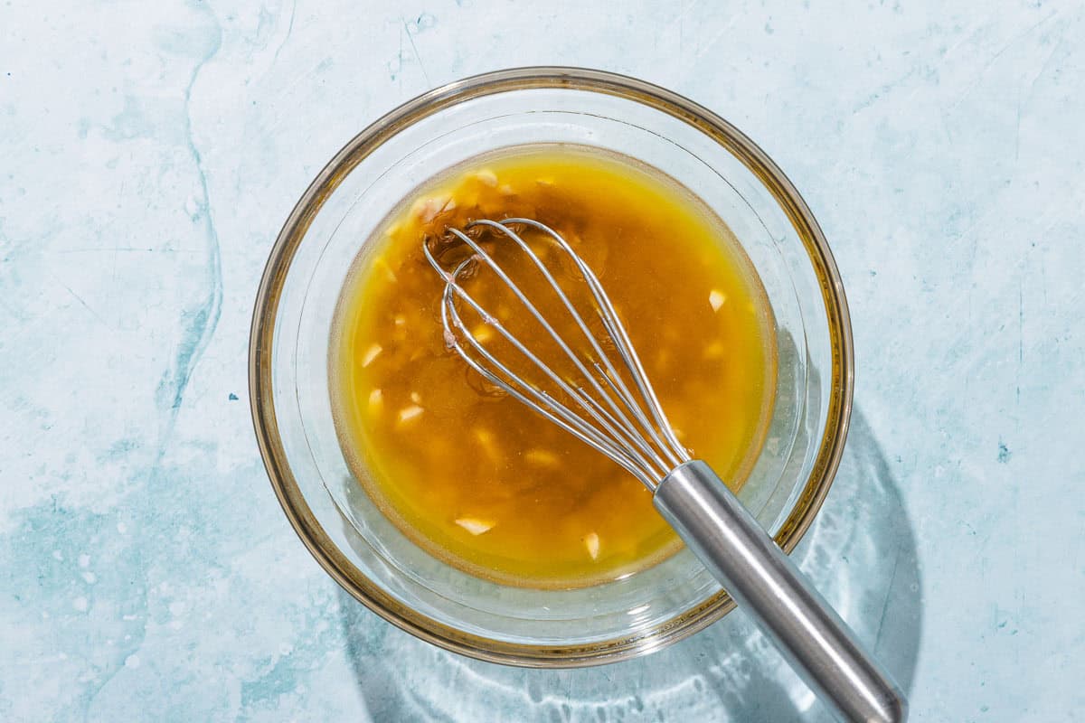 The dressing for the pan bagnat in a bowl with a whisk.