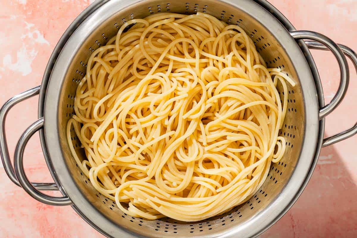 The spaghetti for the shrimp pesto pasted in a strainer.