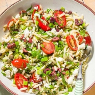 Orzo salad in a bowl with a spoon.