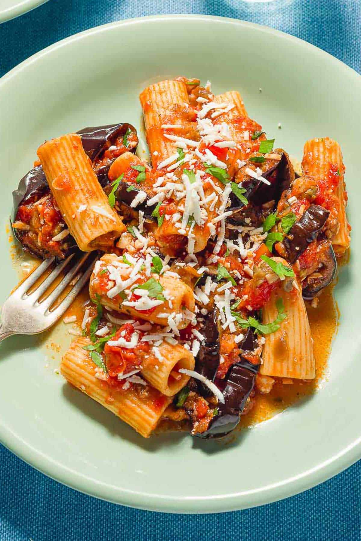 A serving of pasta alla norma on a plate with a fork.