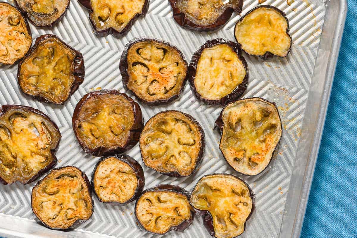 Slices of roasted eggplant spread evenly on a sheet pan.