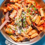 Pasta alla norma in a skillet with a wooden spoon.