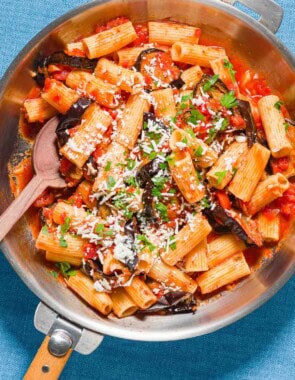 Pasta alla norma in a skillet with a wooden spoon.