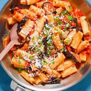 Pasta alla norma in a skillet with a wooden spoon.