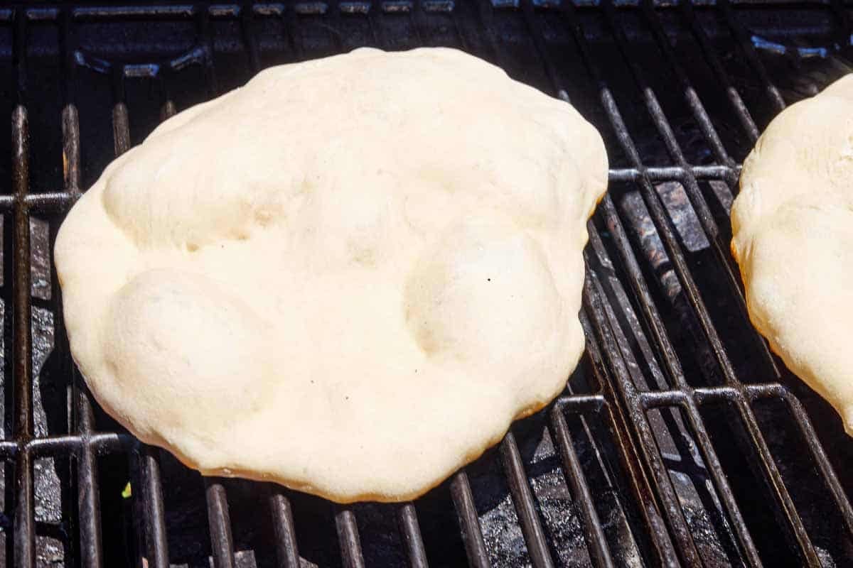The crust for the grilled pizza being grilled on a grill.