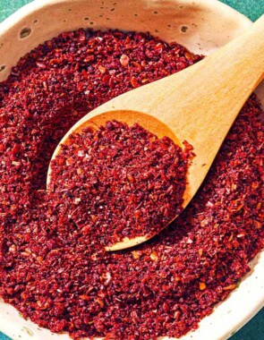 A bowl of sumac with a spoon.