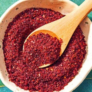 A bowl of sumac with a spoon.