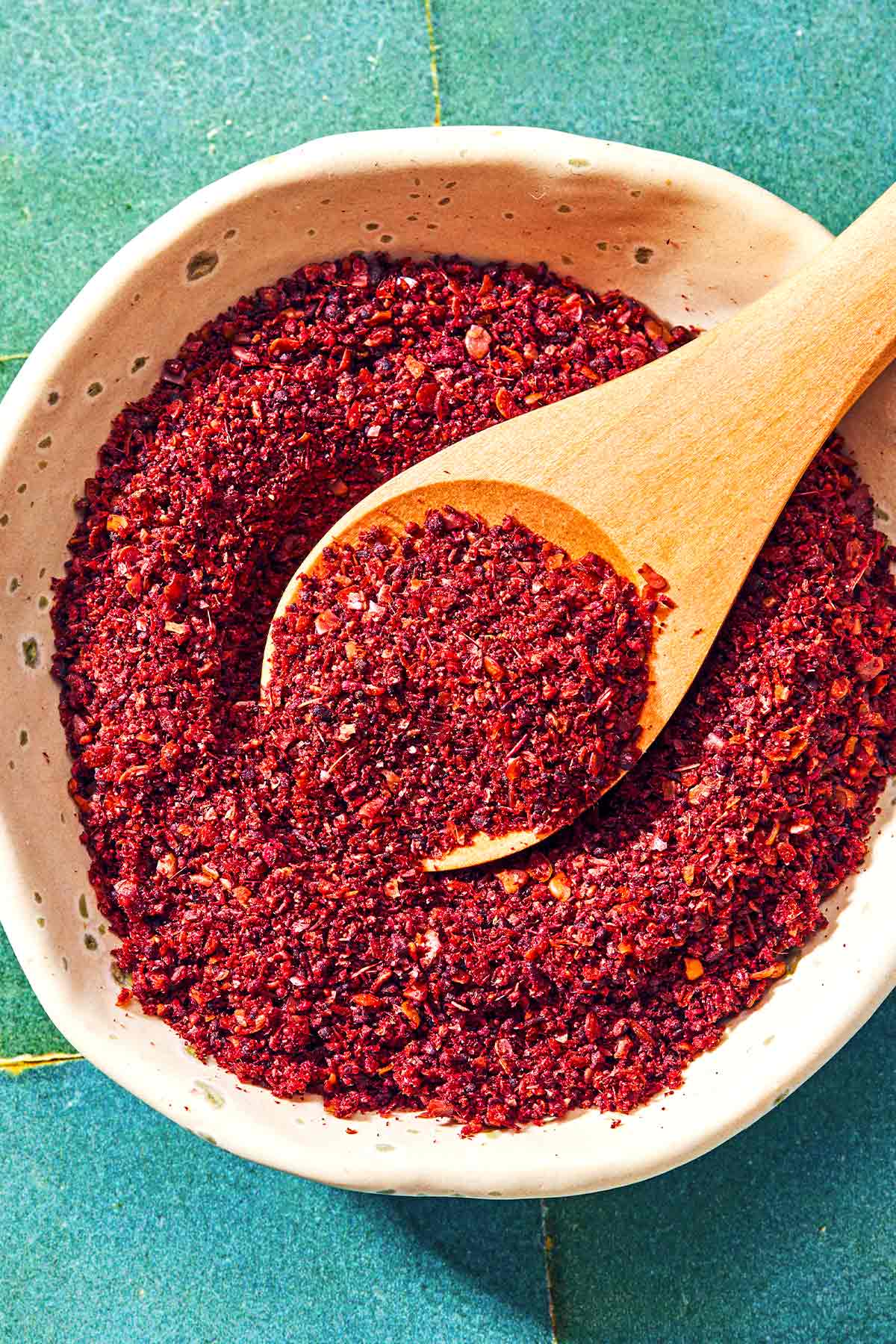 A bowl of sumac with a spoon.