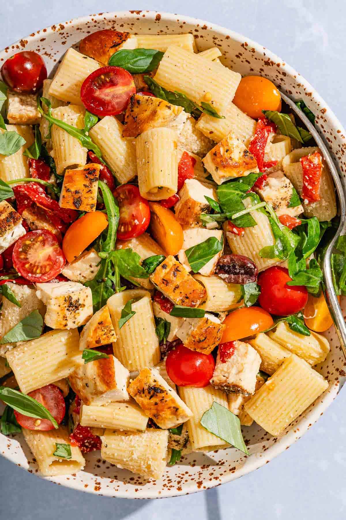 Chicken pasta salad in a serving bowl with a spoon.