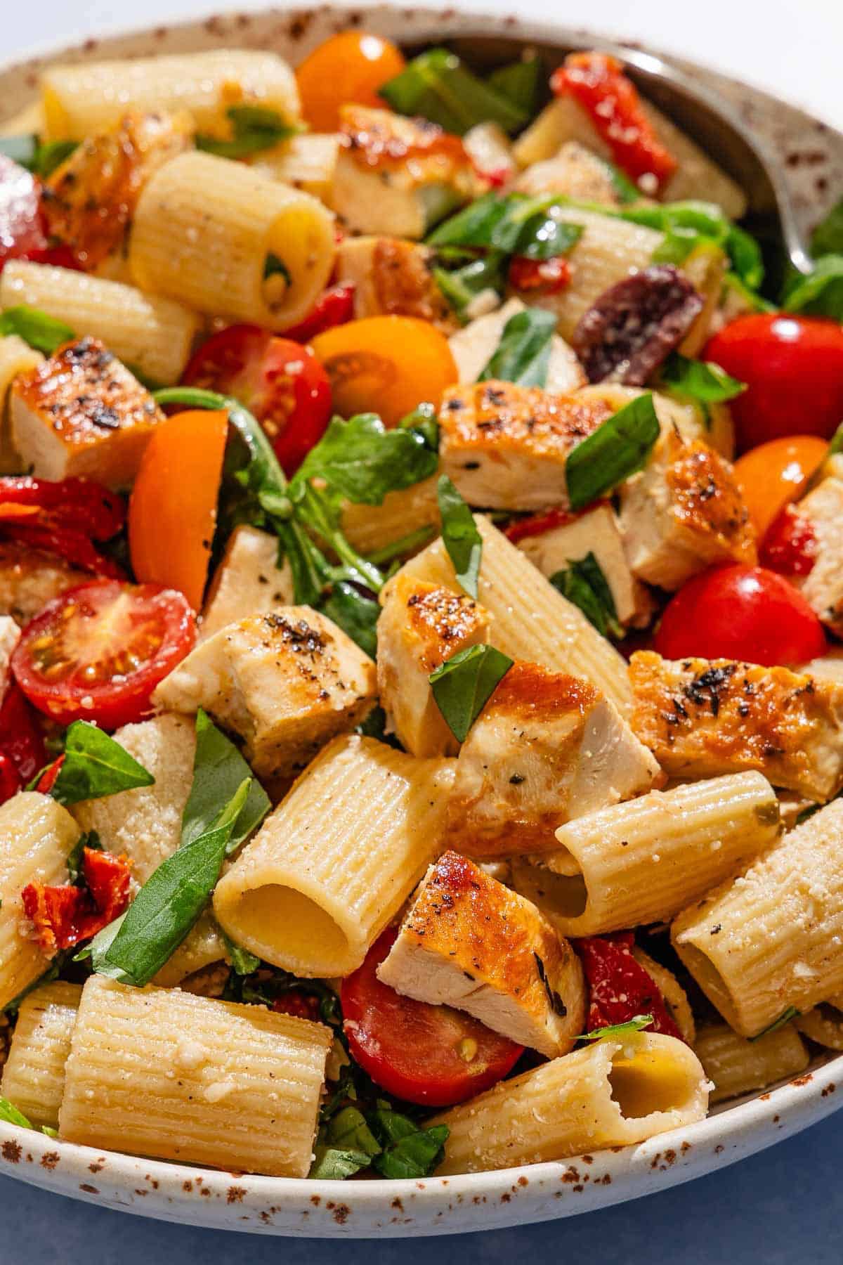 Chicken pasta salad in a serving bowl with a spoon.