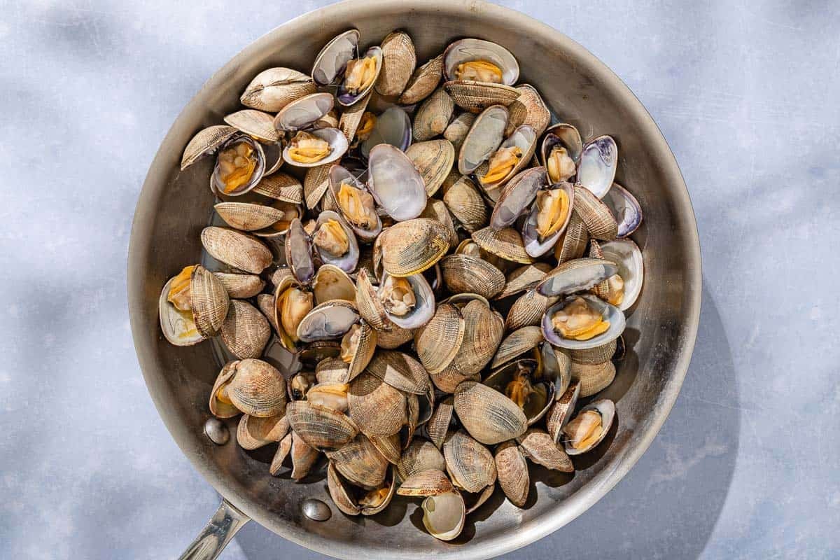 The clams for the seafood salad in a skillet.