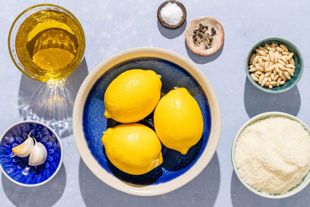 Ingredients for lemon pesto including lemons, olive oil, pine nuts, salt, black pepper, garlic and grated Parmigiano-Reggiano cheese.
