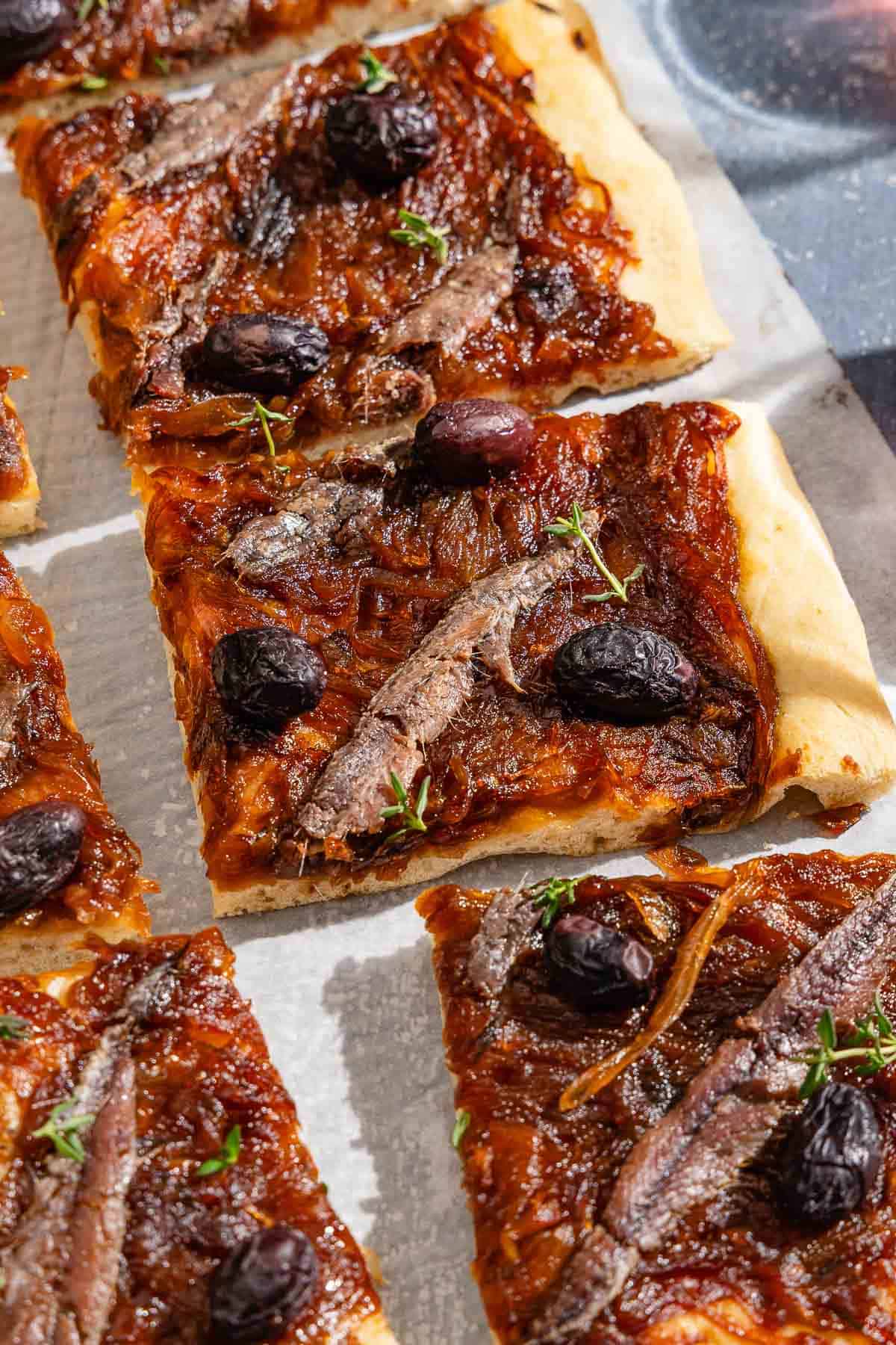 Sliced Pissaladière on parchment paper.